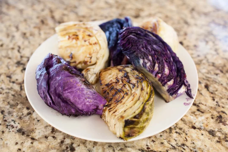 Grilled red and green cabbage wedges with char marks on a white plate, made on a Hasty Bake Charcoal Grill