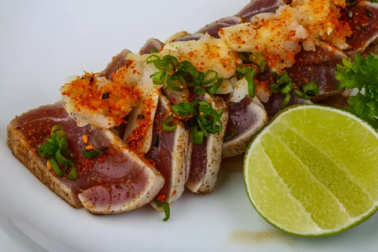 Sliced seared ahi tuna topped with Hasty Bake rub, chili flakes and scallions with lime wedge, cooked on a Hasty Bake Charcoal Grill