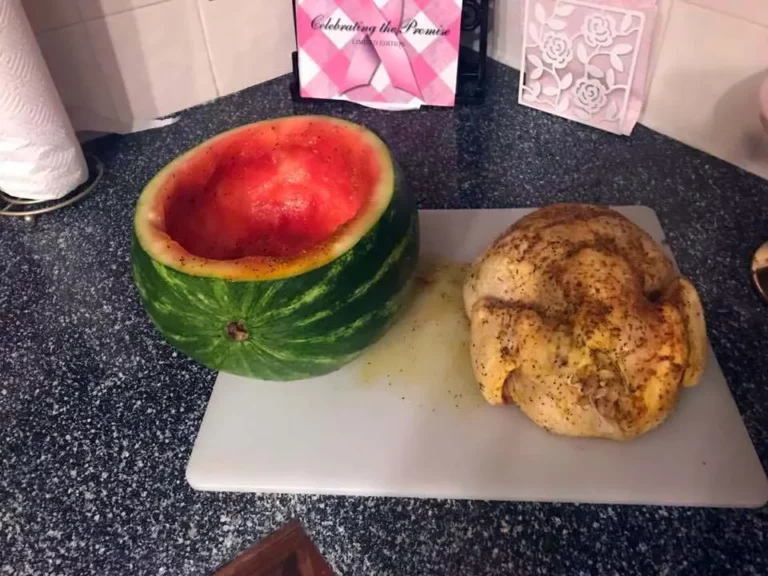 Prep step for Smoked Watermelon Chicken showing hollowed-out watermelon next to raw seasoned whole chicken on a cutting board, for Hasty Bake Charcoal Grill