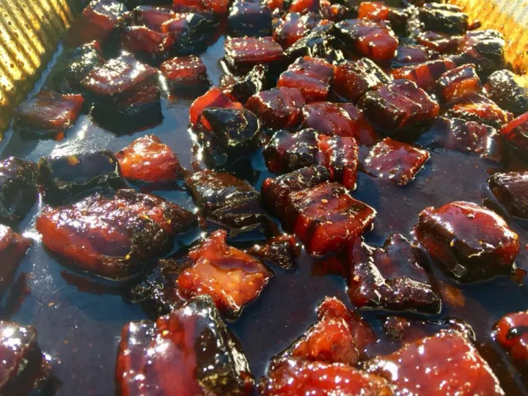 Pork belly burnt ends with dark caramelized glaze in a pan, made on a Hasty Bake Charcoal Grill