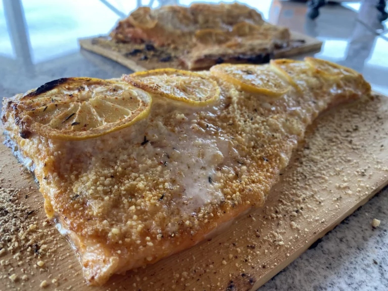 Parmesan crusted salmon fillet with lemon slices on a cutting board, cooked on a Hasty Bake Charcoal Grill