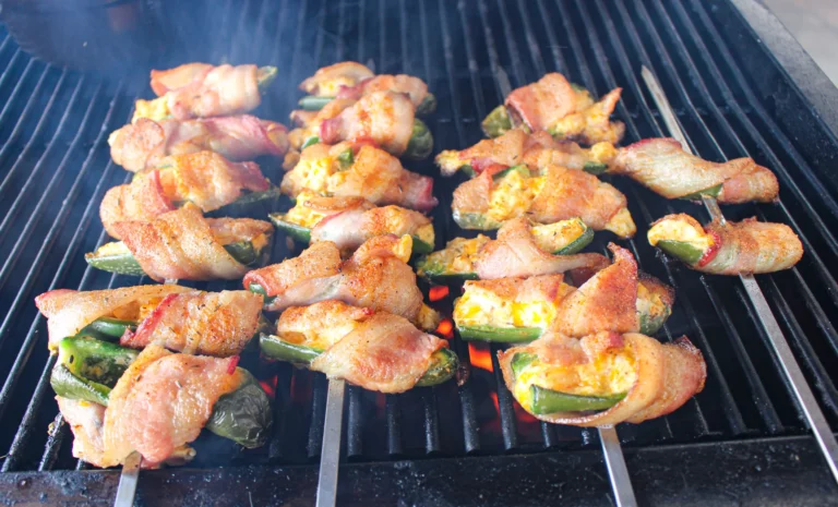 Shrimp jalapeño poppers wrapped in bacon grilling on the grates of a Hasty Bake Charcoal Grill