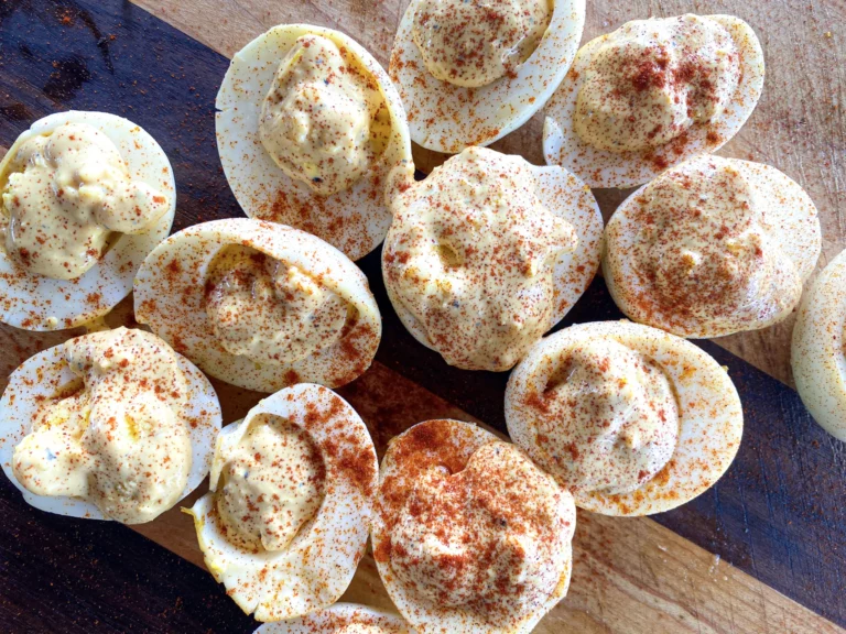 Smoked deviled eggs topped with paprika on a wooden board, made on a Hasty Bake Charcoal Grill