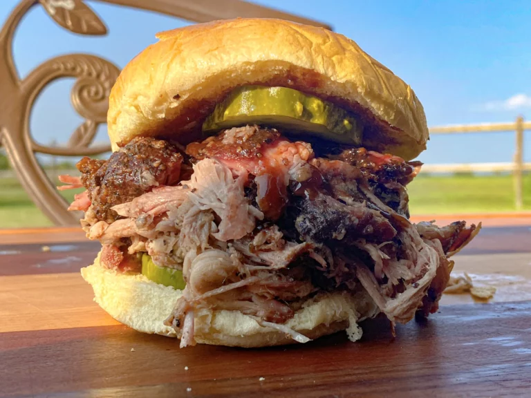 Massive pulled pork sandwich with pickles piled high on a brioche bun, made on a Hasty Bake Charcoal Grill