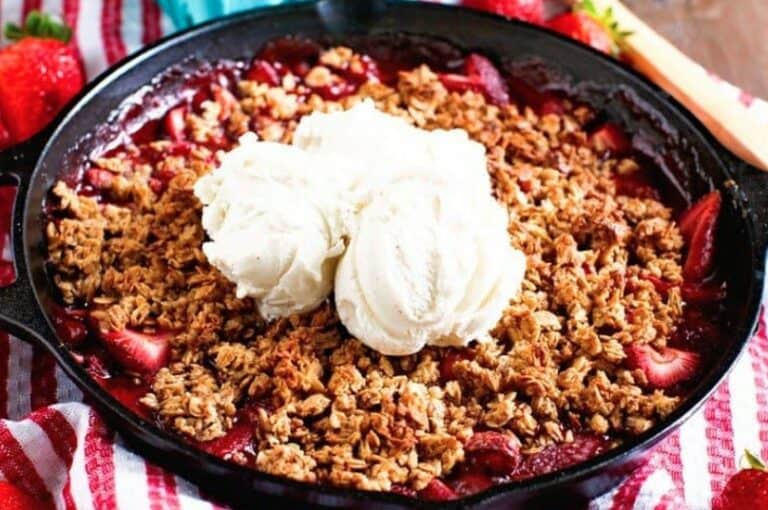 Smoked strawberry crisp in a cast iron skillet topped with two scoops of vanilla ice cream, made on a Hasty Bake Charcoal Grill