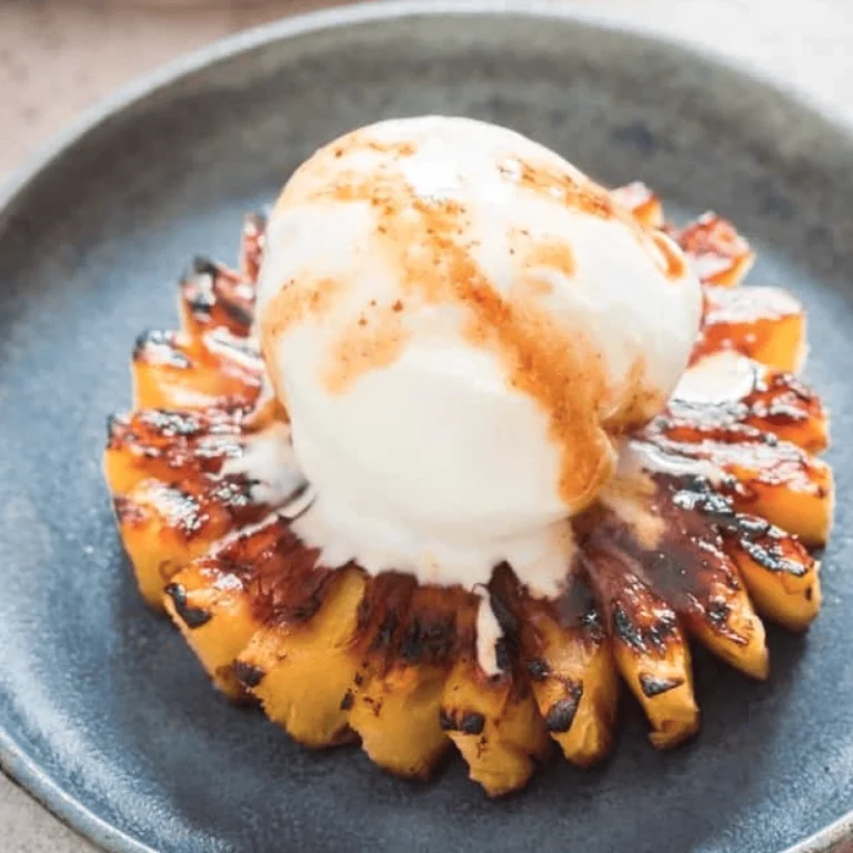 Grilled pineapple slices with brown sugar rum glaze on a plate topped with vanilla ice cream, grilled on a Hasty Bake Charcoal Grill